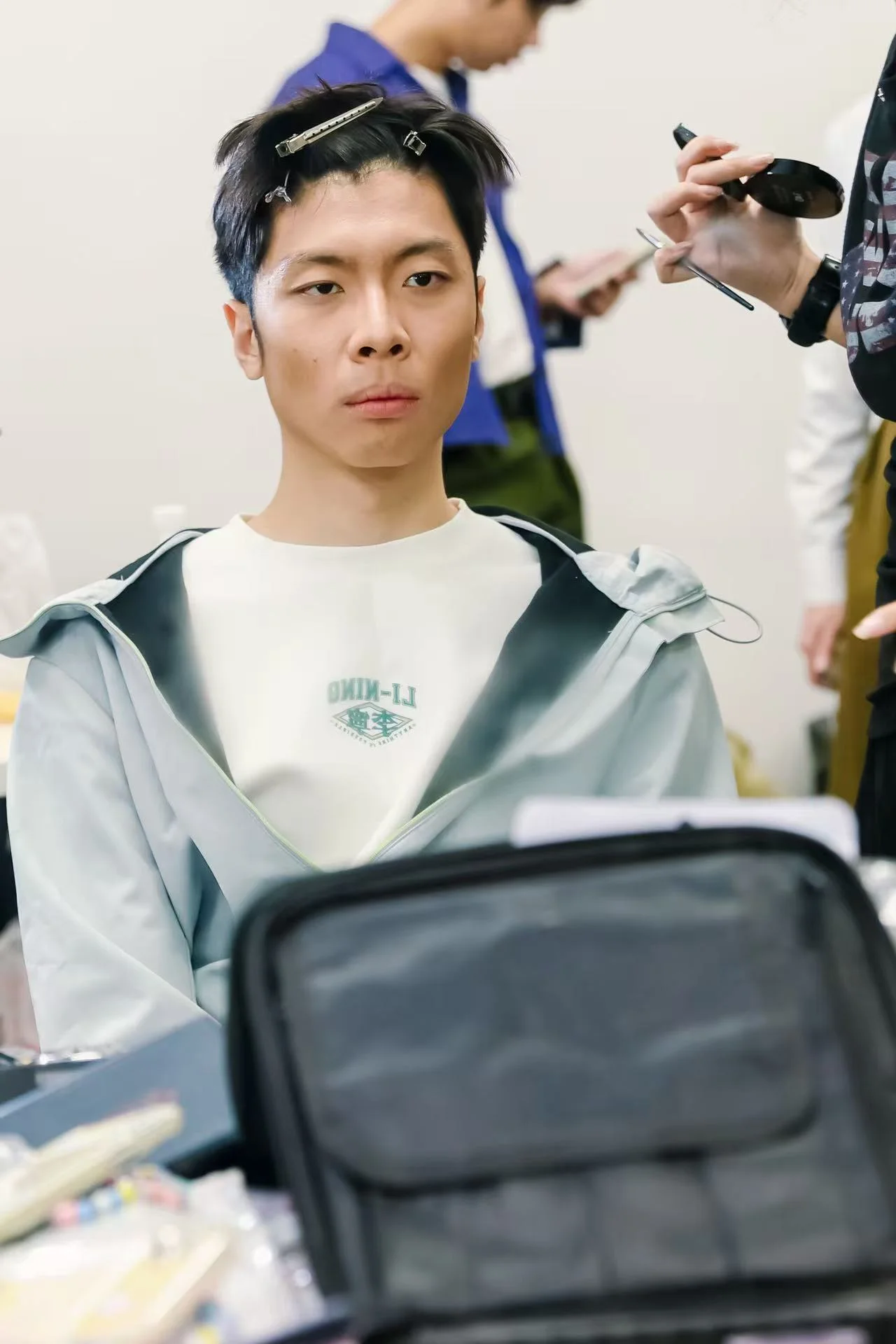 A backstage close-up during makeup, with hair clips, a compact and a makeup brush