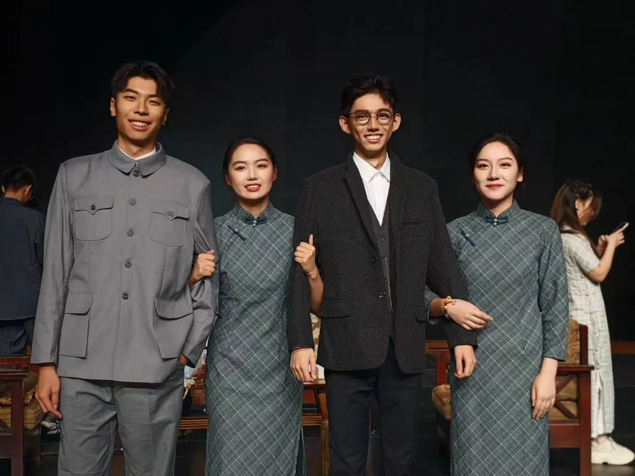 Four friends in costume smiling for a photograph in front of the stage set