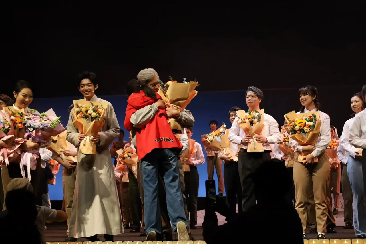 Performers holding bouquets after the show, with one actor embracing someone who brought flowers