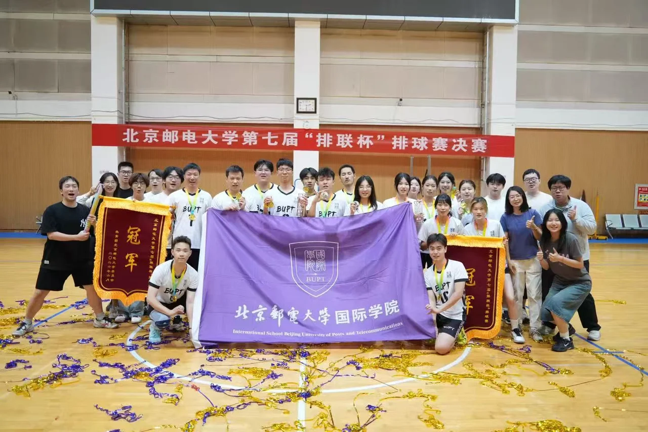 International School players and friends posing with medals, a purple college flag and two championship banners