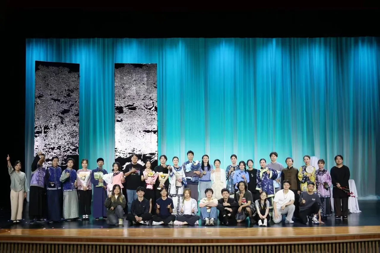 The Family company posing in front of a blue curtain, with some actors in costume holding bouquets