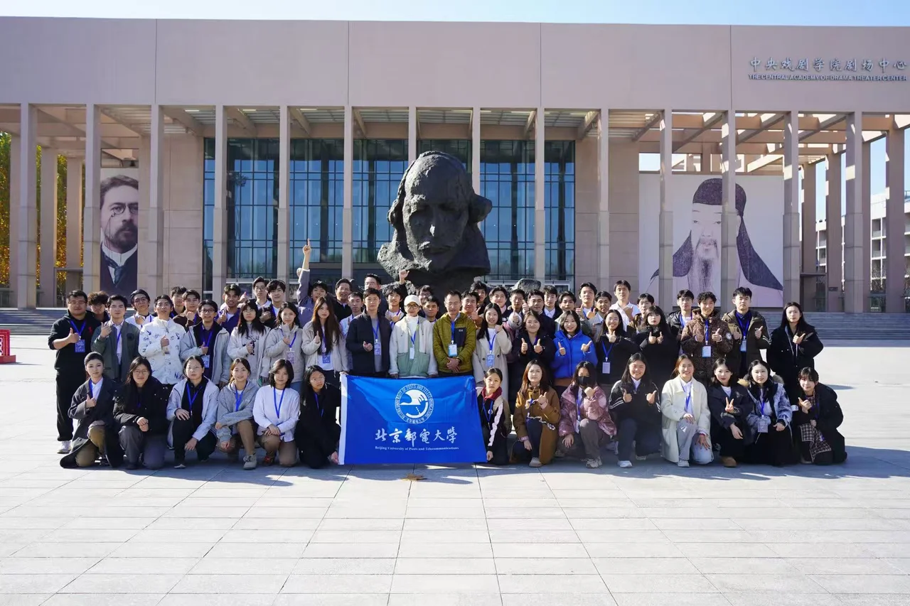 The company posing with a BUPT flag outside the Central Academy of Drama Theater Center