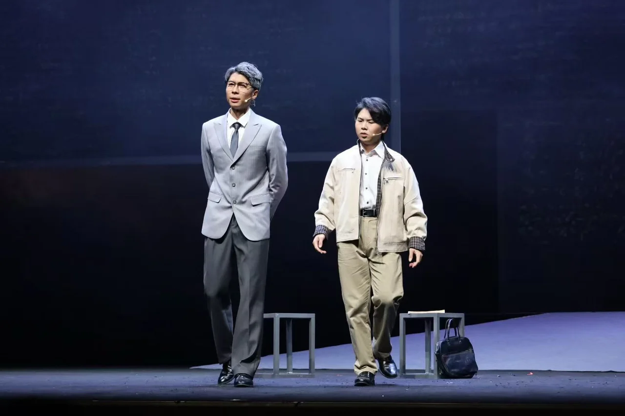 Ye Peida with gray hair and glasses standing beside another actor on stage in Walking with Light